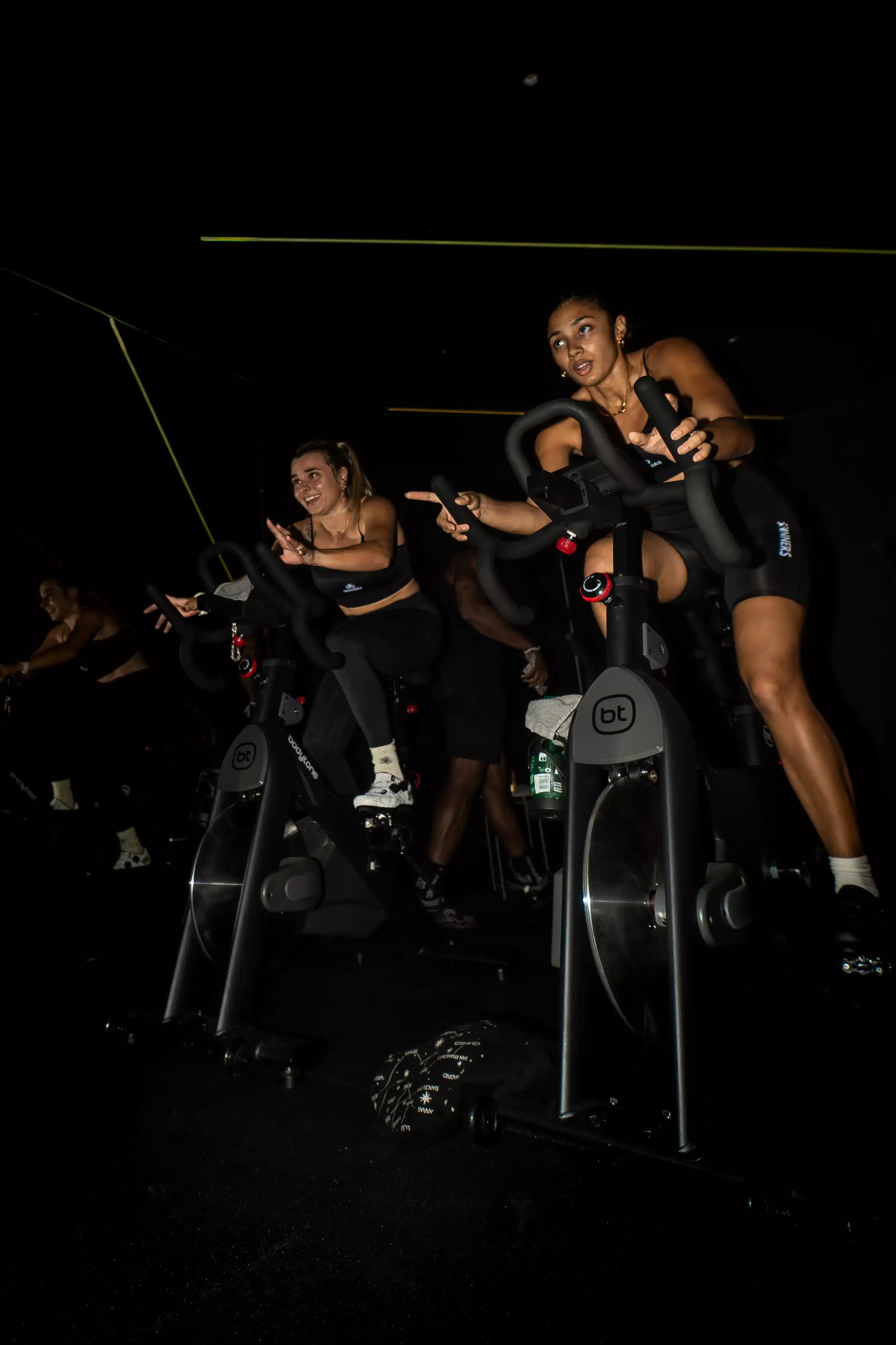 Deux participantes pédalent en danseuse sur les vélos du studio Spinners Cycling à Toulouse