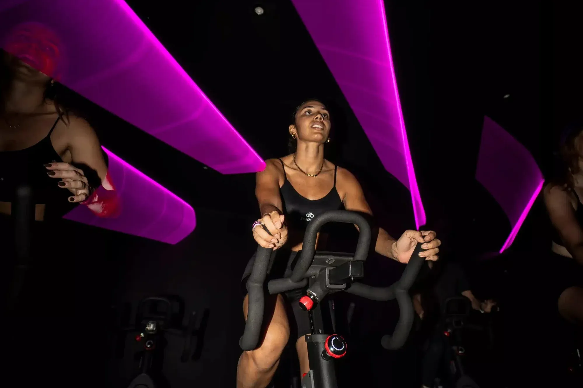 Une participante pédale sous les lasers roses du studio toulousain