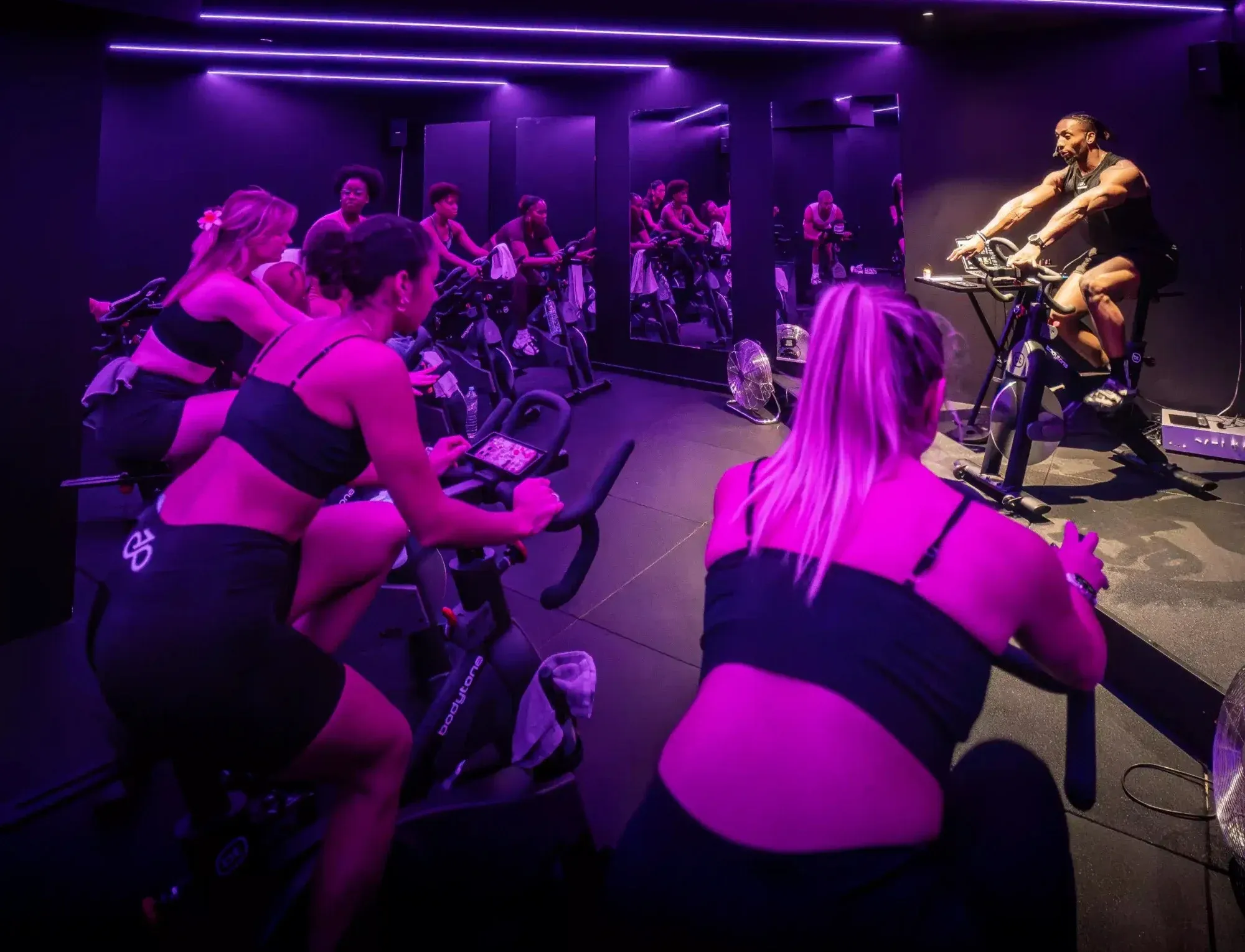 Un cours de cycling au studio Spinners Cycling de Toulouse, le coach face au groupe sous les néons violets