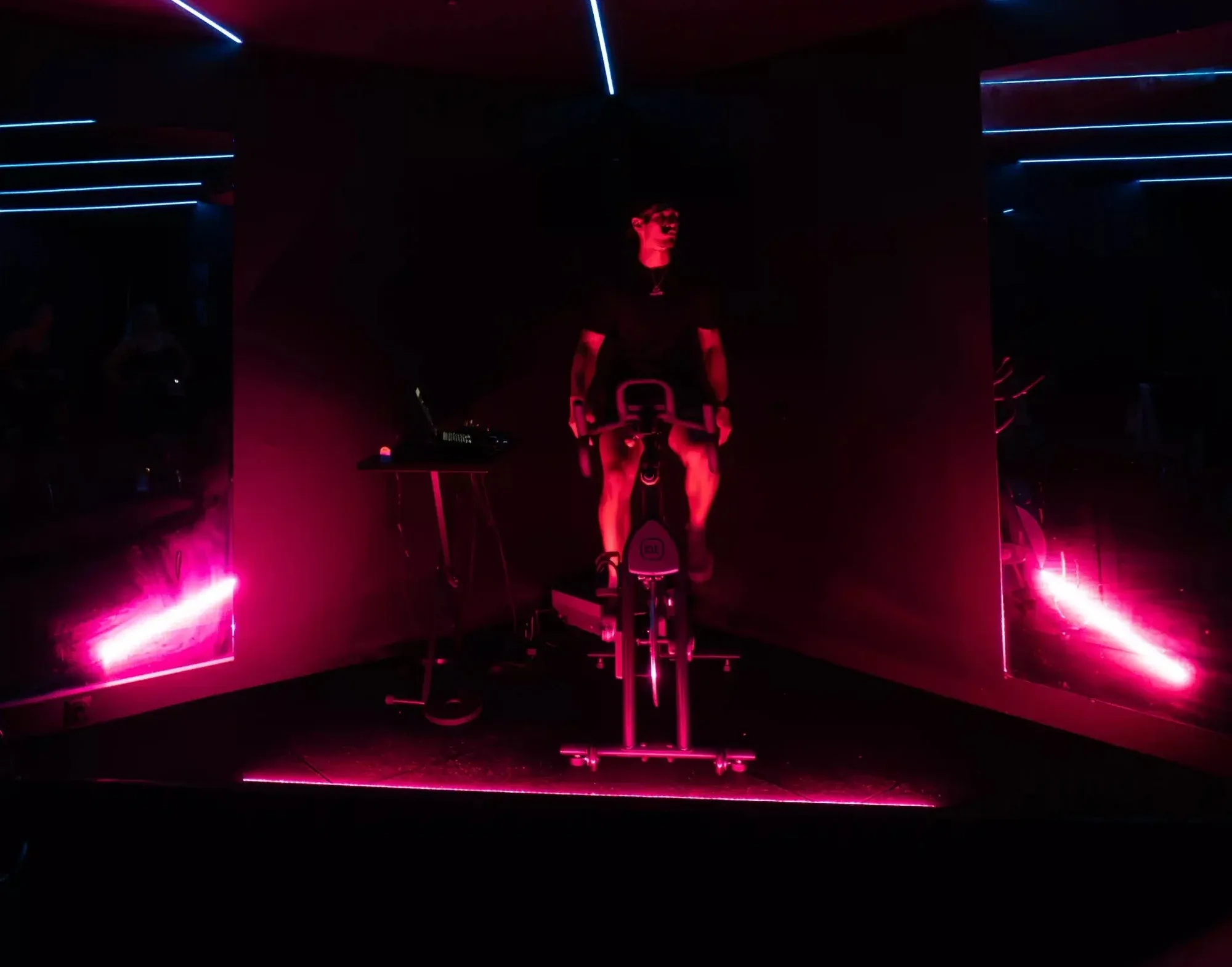 Un coach pédale sur l'estrade du studio Spinners Cycling à Toulouse, dans une lumière rouge